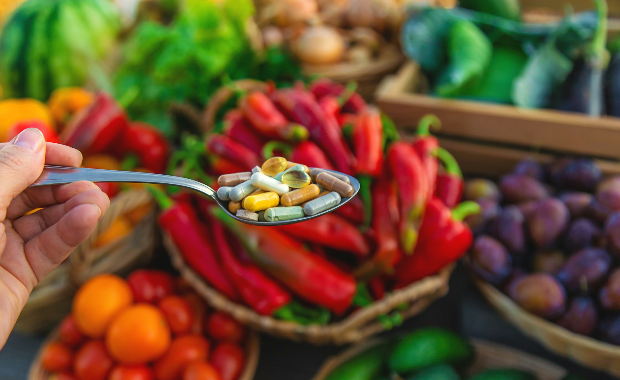 Vitamins and supplements in a spoon with vegetables. Selective focus.